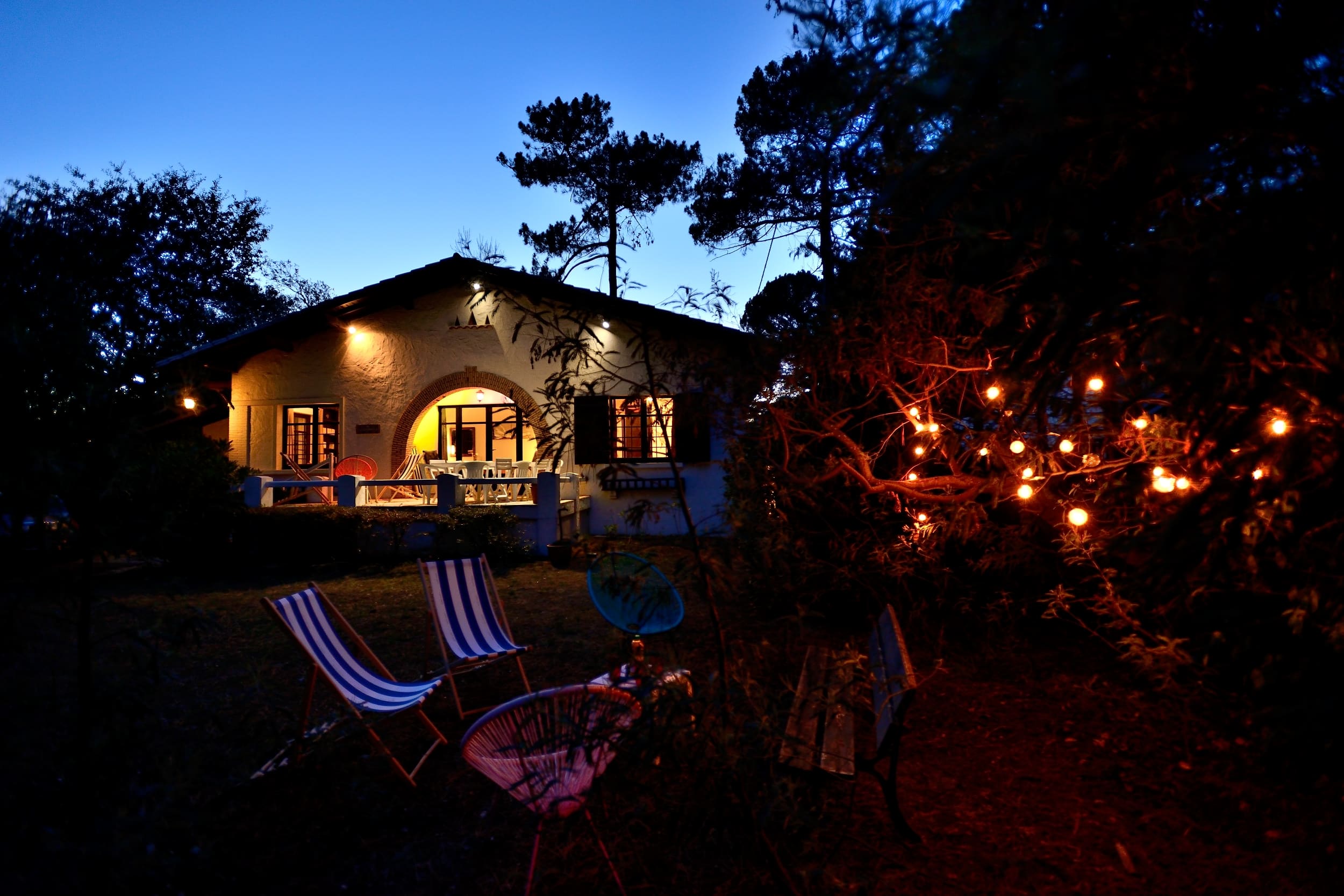 Vue au coucher de soleil de la façade de la Villa la Garrigue au Pyla, du jardin et du salon de jardin