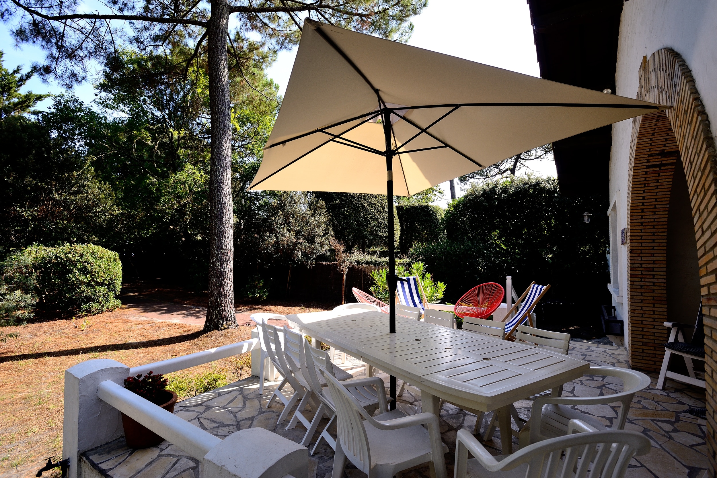 La terrasse de la villa la Garrigue au Pyla avec une table pour les repas,, un espace détente et la vue sur le jardin
