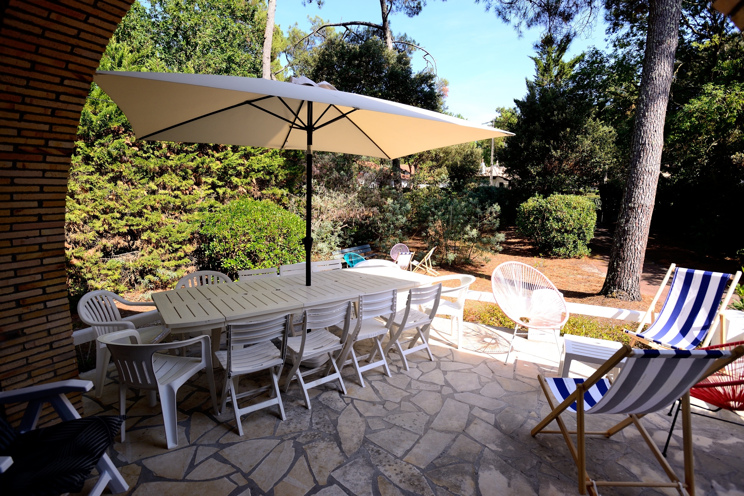 La terrasse de la villa la Garrigue au Pyla avec une table pour les repas, un espace détente, la vue sur le salon de jardin et le jardin