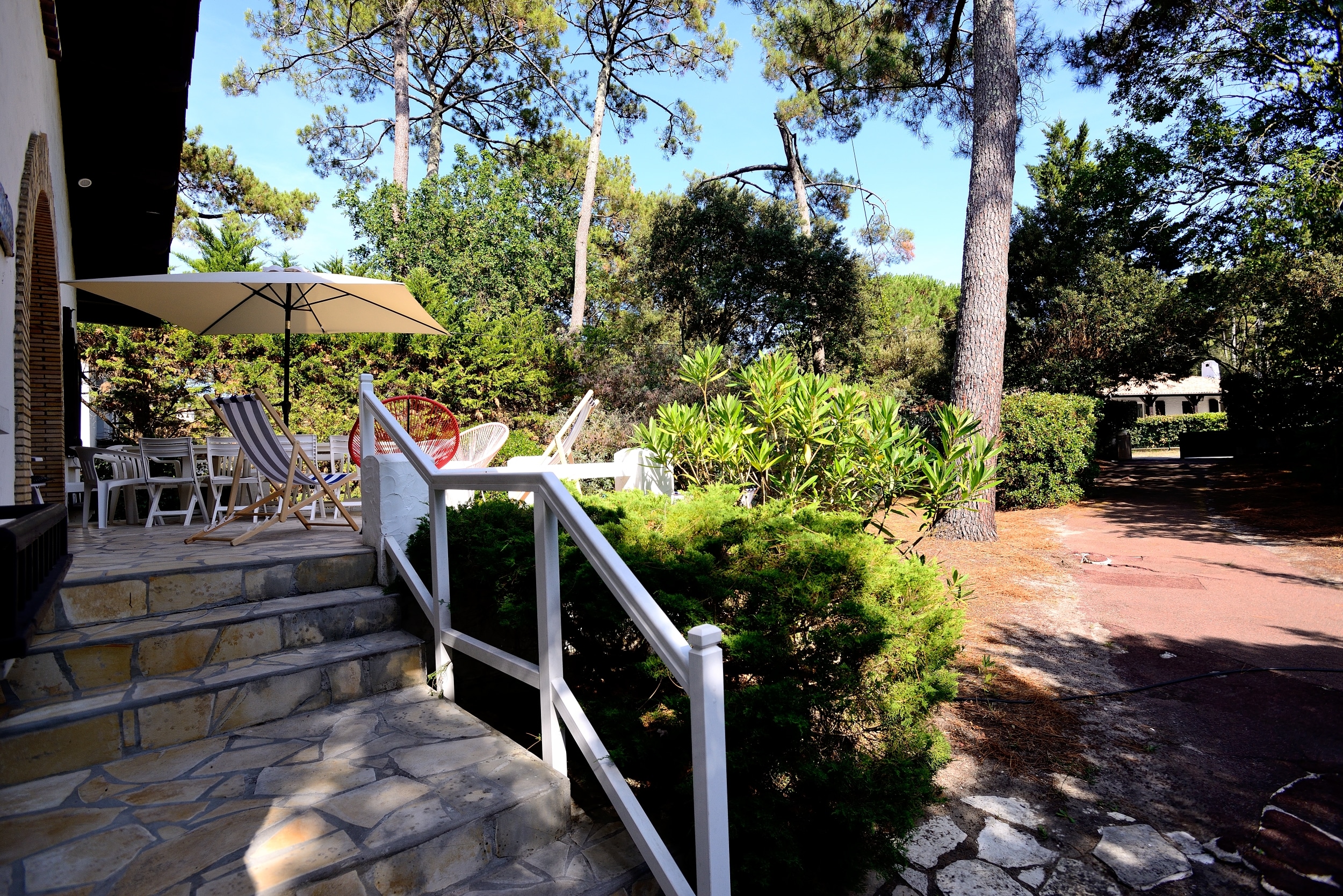 L'accès par quelques marches à la terrasse de la villa la Garrigue au Pyla avec une table pour les repas et un espace détente